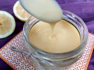 Homemade Lemon Curd dripping of a spoon into a jar.