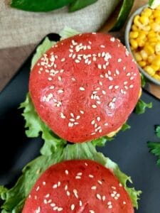 Close-up of dragon fruit burger buns filled with vegetable and lettuce leaves. 