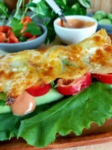 Close-up of baked potato base filled with Veggie and a drizzle of sauce. 
