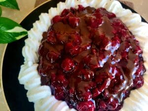 Chocolate cake filled with cherries and garnished with whipped cream.