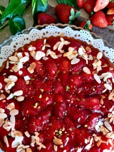 Strawberry Cake topped with chopped pistachios and garnished with sliced almonds