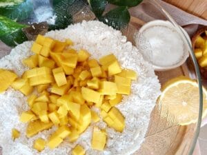 A close up of diced mango tossed in the flour mixture.