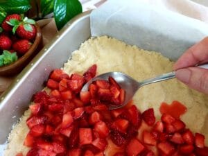 Spreading strawberry filling evenly over the cake base.