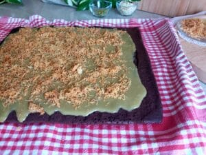 Cocoa Sponge with a layer of pistachio cream filling topped with crunchy kataifi ready to be rolled into a log shape.