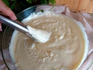 Folding the flour into the beaten egg and sugar mixture using a whisk. 