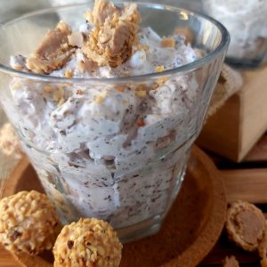 Giotto Cream Dessert in a glass with scattered Giottos on a wooden table.