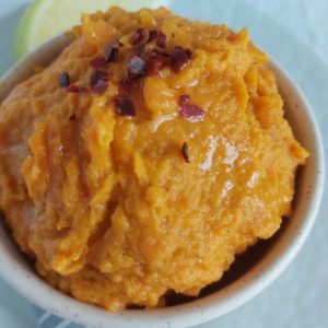Carrot Spread in a dish sprinkled with chilli flakes.