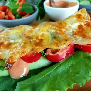 Close-up of baked potato base filled with Veggie and a drizzle of sauce.